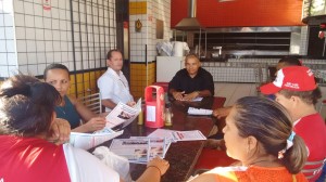 Luiz Henrique sentado à mesa com os trabalhadores.